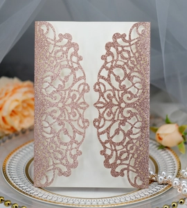 Macro detail of laser-cut rose gold glitter wedding invitation with intricate scrollwork
