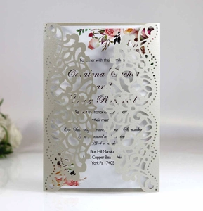 Detail of laser-cut wedding invitation with elegant vine patterns and floral inner card