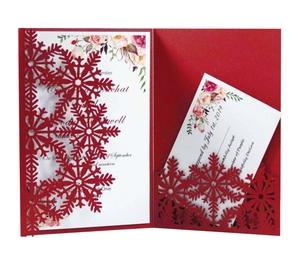 Macro detail of laser-cut red snowflake outer shell and watercolor floral invitation insert