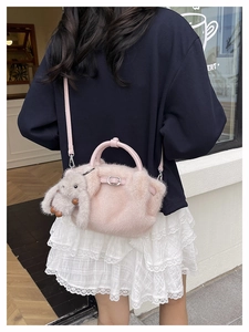 Détail du sac seau en fausse fourrure rose avec breloque lapin porté à l'épaule