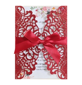 Detail of red glitter laser-cut invitation with satin bow and floral inner card
