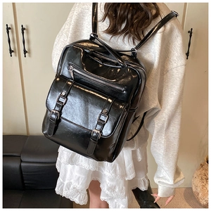 Rear view of a model wearing the black glossy vintage large capacity backpack with silver buckles