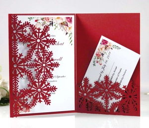 Macro detail of laser-cut red snowflake card with floral inner sheet and RSVP