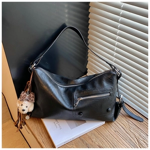 Detail of black faux leather shoulder bag with zipper pocket and plush dog charm