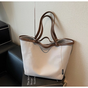 Detail of canvas tote bag with brown leather handles and brand label on a book