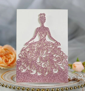 Macro detail of laser-cut wedding card featuring pink glitter gown silhouette design