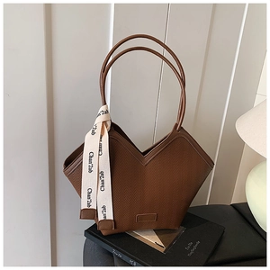 Detail of dark brown tote bag featuring deep V-shape and woven wave texture with ribbon