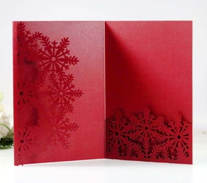 Macro shot of red laser-cut snowflake details on pearlescent paper holiday card