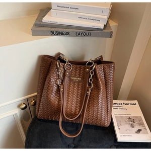 Vue détaillée d'un sac cabas tressé marron avec chaîne dorée sur des livres d'art