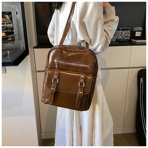 Detail of dark brown vintage faux leather backpack with metallic buckles and glossy finish