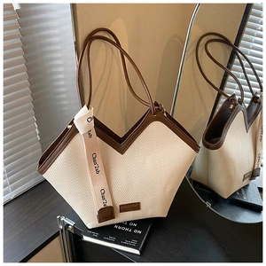 Detailed close-up of woven chevron texture and leather handle on the cream tote bag