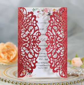 Detail of red glitter laser cut wedding invitation with floral insert on elegant plate