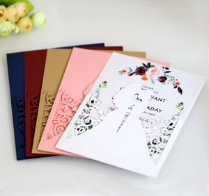 Detail showing multi-color laser-cut wedding invitation covers with floral inner cards