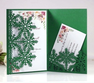 Detail showing laser-cut snowflake patterns on dark green holiday invitation card