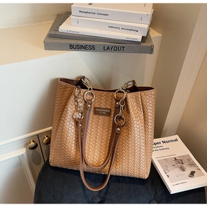Détail du sac cabas marron tissé avec écusson logo en cuir et sangle de chaîne
