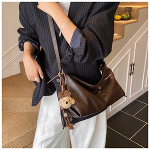 Detailed view of brown PU leather shoulder bag with side zipper and plush bear pendant