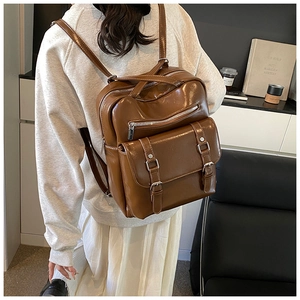 Brown vintage PU leather backpack with buckle flap and zippers shown in use by model