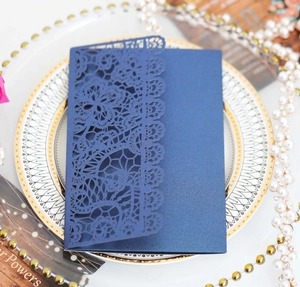 Detail of dark blue laser-cut lace wedding invitation card with intricate floral patterns
