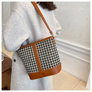 Detail of houndstooth bucket bag with brown leather trim and fine white contrast stitching
