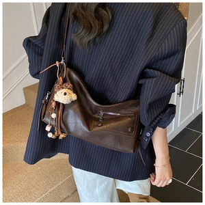 Detail of dark brown leather crossbody bag with teddy bear charm and soft PU texture