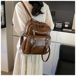 Brown vintage faux leather backpack shown on a model for scale and fit in a room