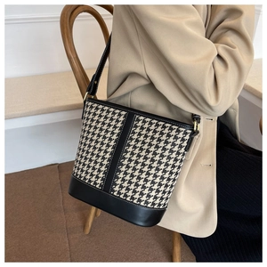 Detail showing houndstooth fabric bucket bag with black leather trim and stitching