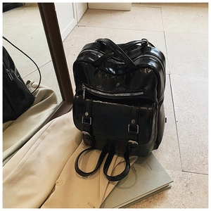 Detail view of glossy black PU leather backpack showing vintage texture and metal buckle