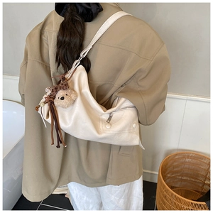Chic beige crossbody bag with cute teddy bear charm and fringe detail on the strap