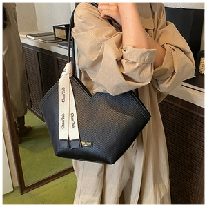 Detail of black tote bag featuring chevron embossed texture and stylish ribbon tie