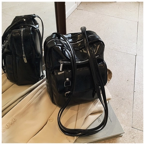 Macro shot of black glossy faux leather backpack featuring silver buckles and buckles