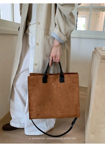 Primo piano di una borsa tote grande in camoscio marrone con manici in pelle nera