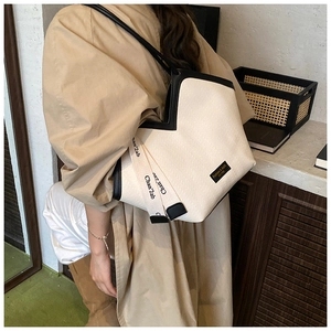 Detail of the knit tote bag with black leather trim and chic ribbon decoration