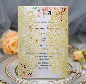 Detail of laser-cut gold glitter wedding invitation with romantic floral printed insert