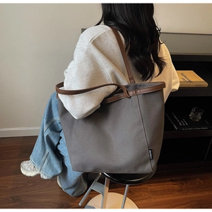 Detail view of large canvas tote bag with brown PU straps shown on a model's shoulder
