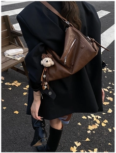 Brown leather underarm bag with irregular design and cute plush dog charm on side