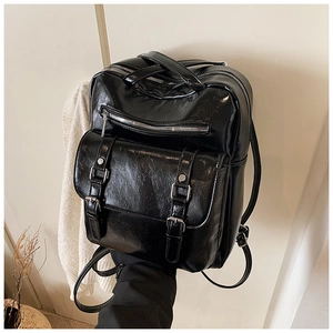 Detailed view of large black glossy leather backpack with silver metallic hardware and buckles