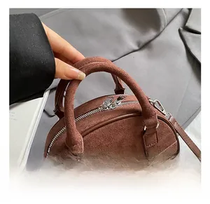 Détail montrant les rivets métalliques argentés et la texture daim marron du sac à main