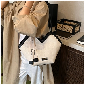 Detail of canvas tote bag with black leather trim and chic herringbone pattern texture