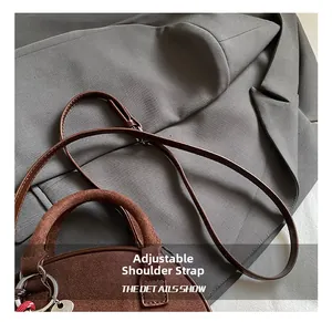Détail de la bandoulière réglable et de l'anneau argenté sur le sac en daim foncé