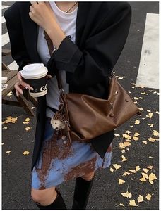 Outdoor shot of brown vintage shoulder bag with cute bear charm and zipper detail