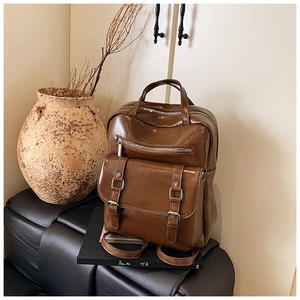 Close-up of vintage brown glossy leather backpack with buckles on a classic leather stool