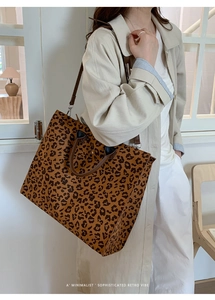 Dettaglio di una grande borsa tote leopardata con manici in pelle marrone indossata da modella