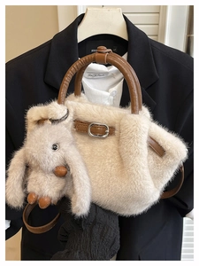Detail der cremefarbenen Plüschtasche mit braunen Ledergriffen und Hasen-Anhänger