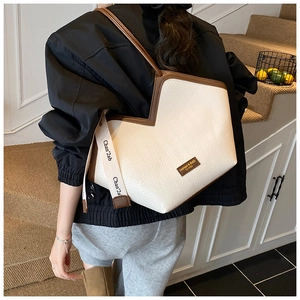 Detail of cream tote bag with herringbone texture, brown leather trim and shoulder strap