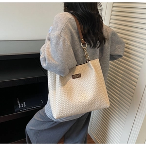 Détail de la texture tressée et de l'étiquette en cuir sur ce sac cabas beige
