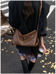 Detail shot of vintage brown leather crossbody bag with tassel and autumn street background