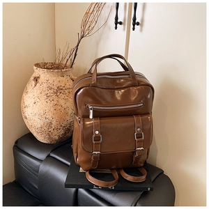 Macro shot of dark brown vintage oil-leather backpack with metal buckles and pockets