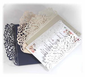 Detail of laser cut wedding invitation with intricate floral vine patterns and inner card