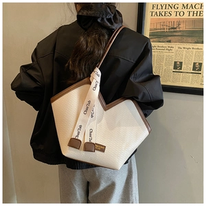 Detail of cream woven tote bag with herringbone pattern and dark brown leather straps
