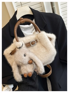 Details einer beigen Plüschtasche mit braunem Ledergriff und süßem Hasen-Anhänger